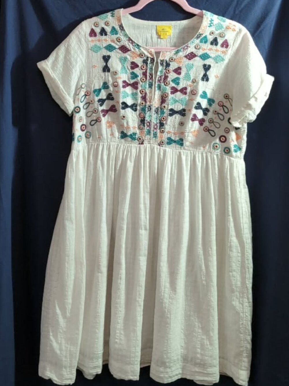 White boho dress with colorful embroidered geometric and bow motifs